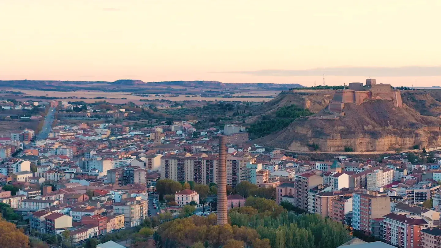 Monzón at dusk, the old factory chimney among the apartment blocks, the castle behind